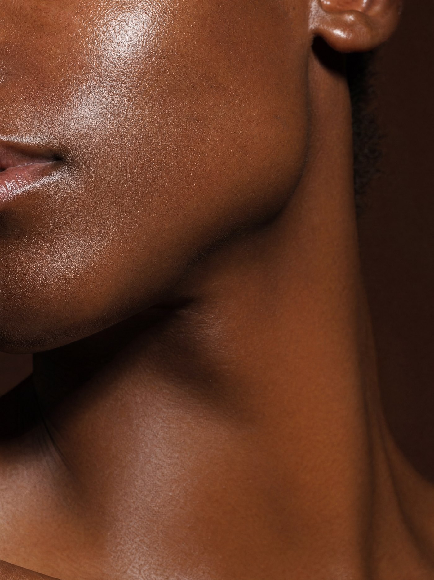 Close-up of luminous melanin-rich skin along the jaw and neck